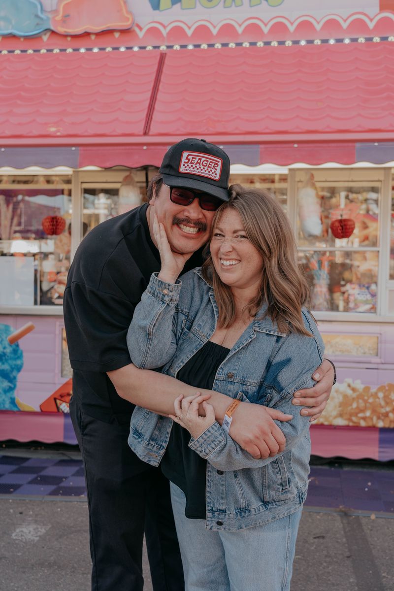 Ryan and Rachel holding each other in front of a pink game stand